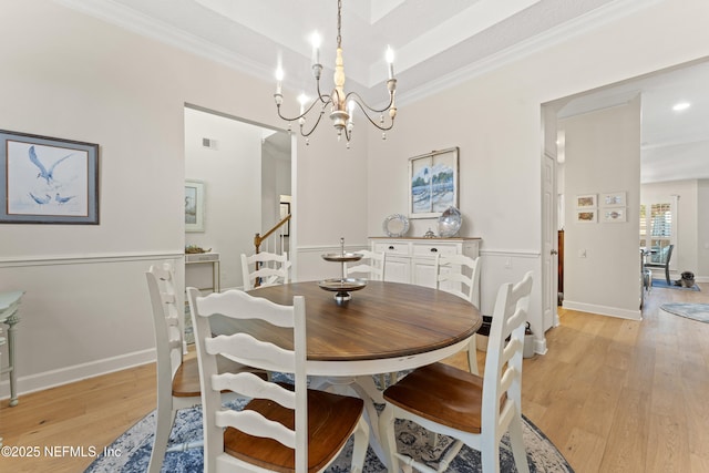 dining space featuring visible vents, crown molding, a raised ceiling, a notable chandelier, and light wood-type flooring