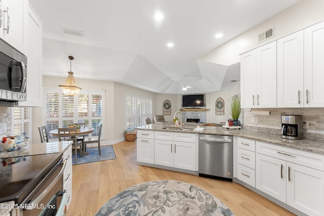 kitchen with visible vents, appliances with stainless steel finishes, a fireplace, a peninsula, and a sink