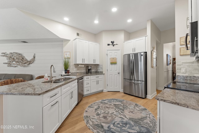 kitchen featuring a sink, light stone countertops, appliances with stainless steel finishes, and white cabinets