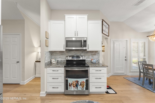 kitchen with visible vents, light wood-style flooring, backsplash, white cabinetry, and stainless steel appliances