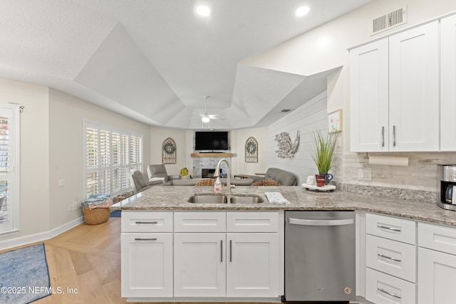 kitchen featuring visible vents, ceiling fan, a peninsula, a fireplace, and a sink