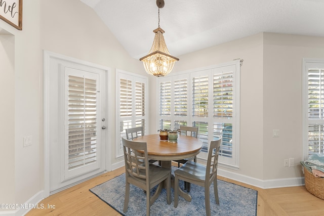 dining area featuring an inviting chandelier, baseboards, light wood-style floors, and vaulted ceiling