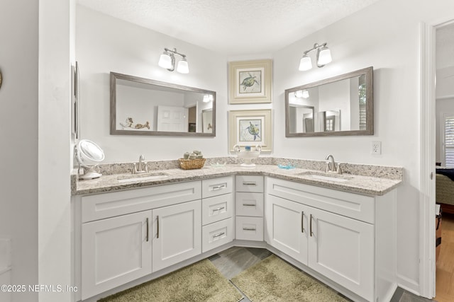 bathroom with double vanity, a textured ceiling, and a sink