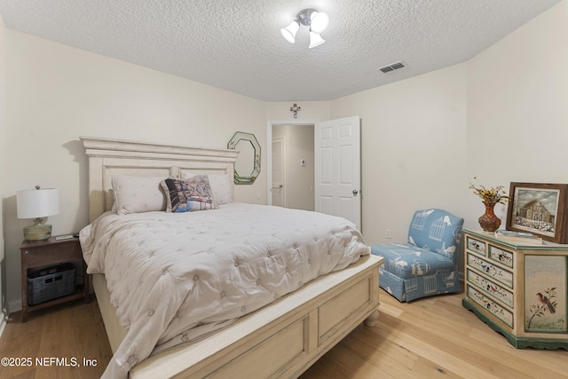 bedroom with visible vents, a textured ceiling, and light wood-style flooring