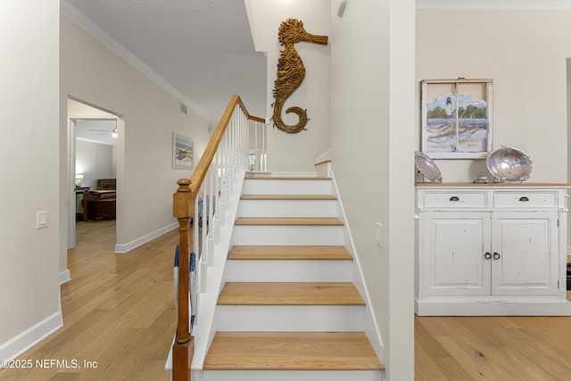 stairs featuring visible vents, crown molding, baseboards, and wood finished floors