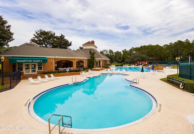 community pool with a patio area and fence