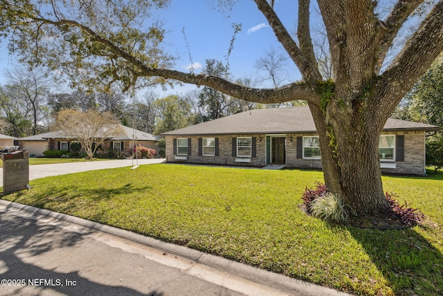 ranch-style house featuring driveway, brick siding, roof with shingles, and a front lawn