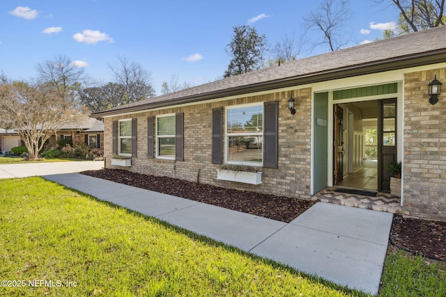 exterior space with brick siding and a yard