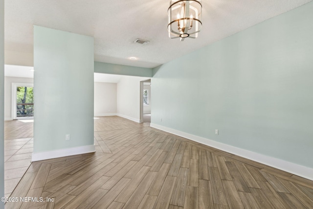 empty room with baseboards, visible vents, a chandelier, and wood tiled floor