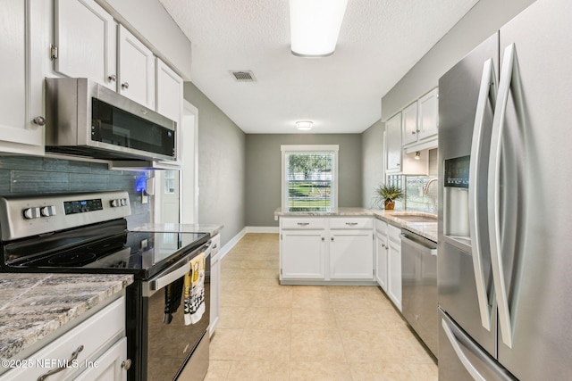 kitchen featuring visible vents, stainless steel appliances, decorative backsplash, and a sink