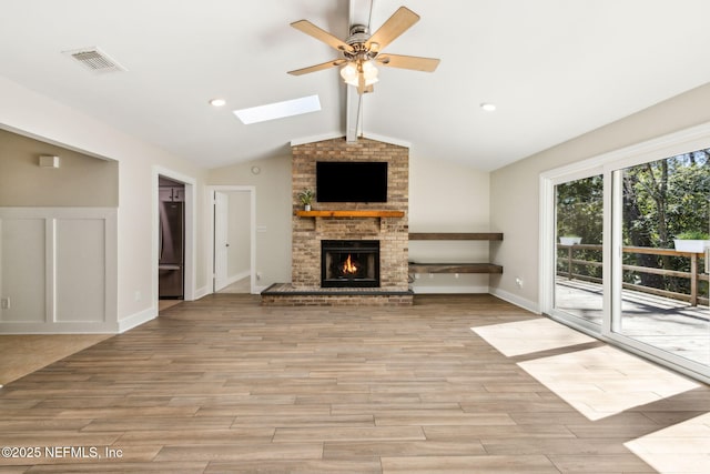 unfurnished living room featuring light wood-type flooring, visible vents, lofted ceiling with skylight, and ceiling fan