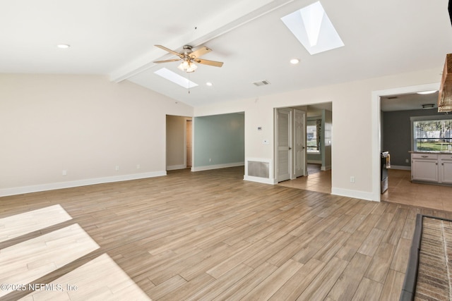 unfurnished living room with light wood-type flooring, lofted ceiling with skylight, visible vents, a ceiling fan, and baseboards