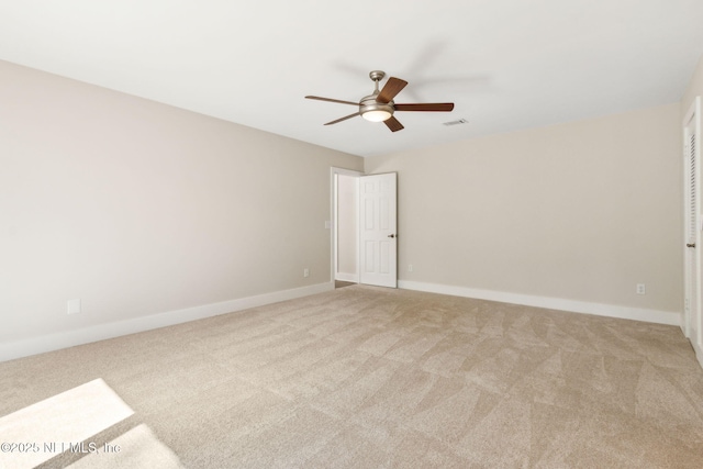 carpeted spare room with visible vents, baseboards, and ceiling fan