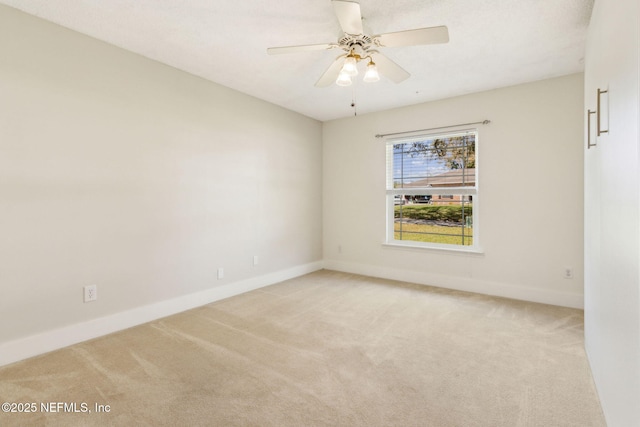 unfurnished room featuring baseboards, light carpet, and a ceiling fan