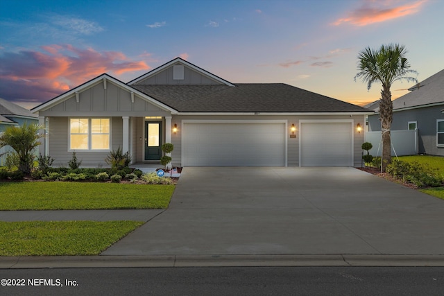 view of front of home with board and batten siding, a front lawn, fence, driveway, and an attached garage