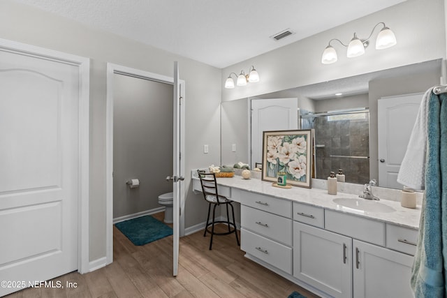 full bathroom with vanity, wood finished floors, visible vents, a stall shower, and toilet