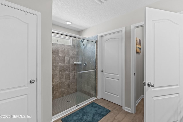 bathroom featuring a stall shower, a textured ceiling, and wood finished floors