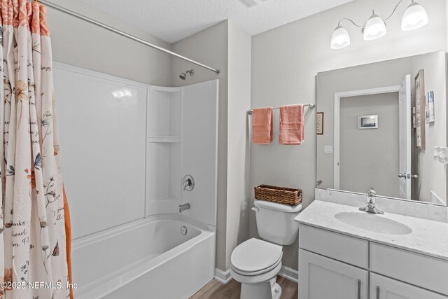 full bath with toilet, vanity, wood finished floors, shower / bath combination with curtain, and a textured ceiling