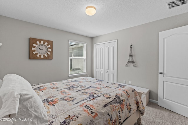 carpeted bedroom with a closet, visible vents, a textured ceiling, and baseboards