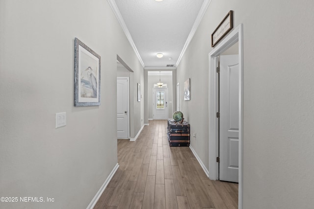 hall featuring baseboards, wood finished floors, and ornamental molding