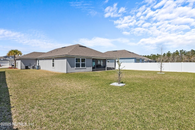 rear view of house with a lawn and fence