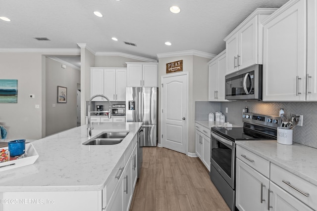 kitchen with a center island with sink, visible vents, a sink, stainless steel appliances, and white cabinetry