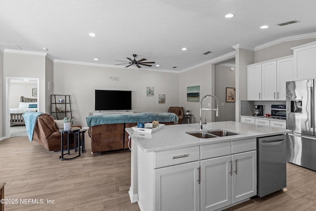 kitchen featuring visible vents, light wood-style floors, stainless steel appliances, a ceiling fan, and a sink