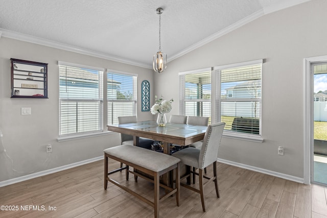 dining area featuring vaulted ceiling, light wood-style flooring, baseboards, and a textured ceiling