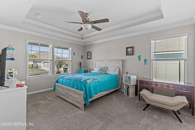 carpeted bedroom featuring a tray ceiling, a ceiling fan, baseboards, and ornamental molding