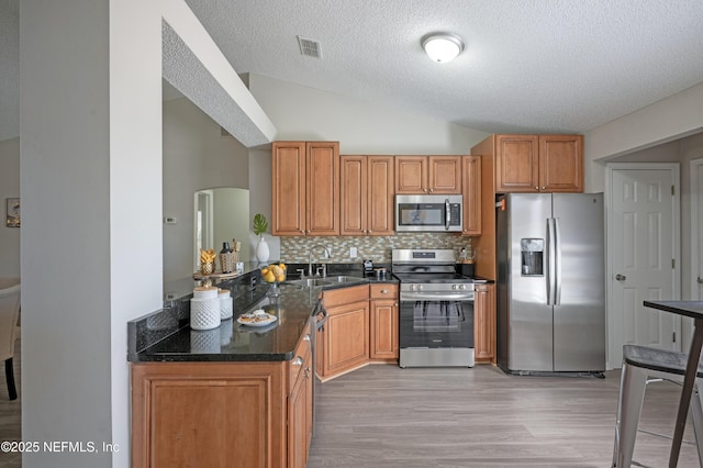 kitchen with visible vents, backsplash, lofted ceiling, stainless steel appliances, and a sink