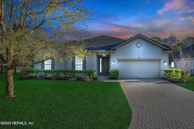 ranch-style house featuring stucco siding, a lawn, decorative driveway, a shingled roof, and a garage