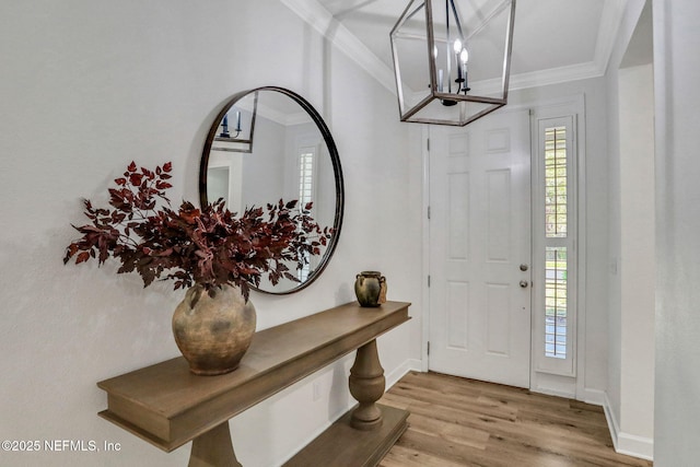 entrance foyer featuring a wealth of natural light, a notable chandelier, wood finished floors, and ornamental molding