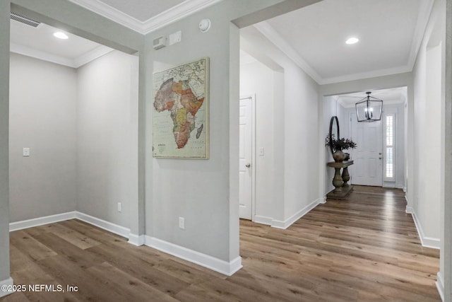 hallway featuring visible vents, a notable chandelier, wood finished floors, and crown molding