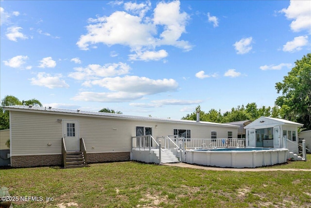 rear view of property with a lawn, an outdoor pool, and entry steps