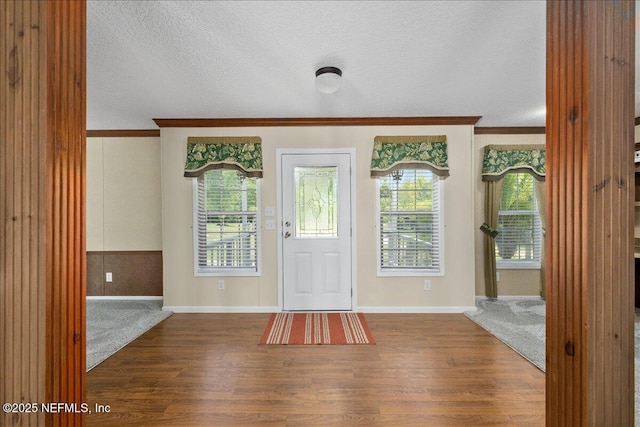 entryway with baseboards, a textured ceiling, wood finished floors, and crown molding