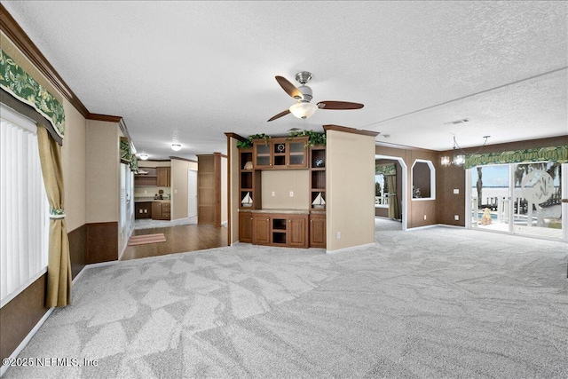 unfurnished living room with ornamental molding, a textured ceiling, ceiling fan, and carpet floors