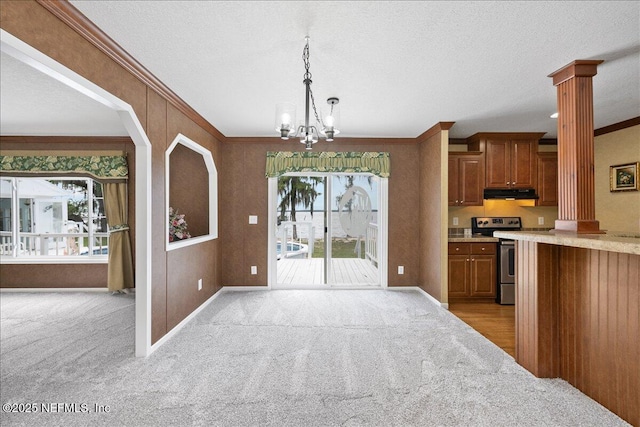 kitchen with brown cabinetry, light countertops, electric stove, under cabinet range hood, and crown molding