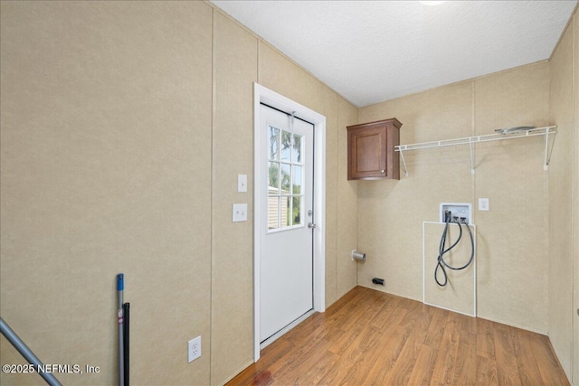 clothes washing area featuring light wood finished floors, cabinet space, and washer hookup