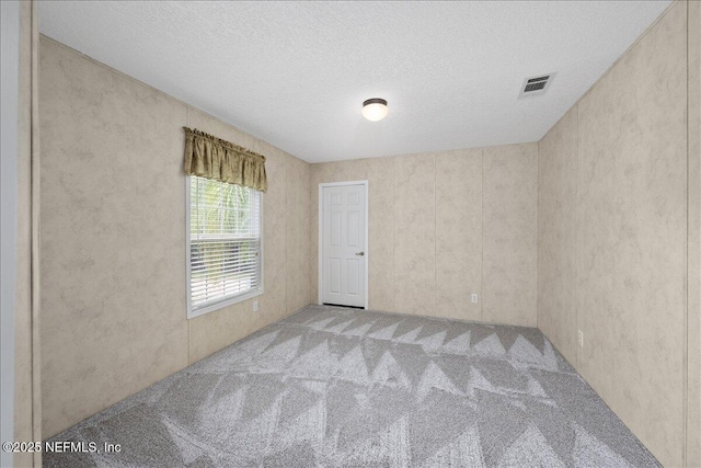 empty room with visible vents, carpet floors, and a textured ceiling