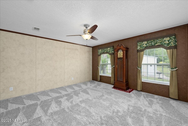 unfurnished room with visible vents, carpet, ceiling fan, and a textured ceiling