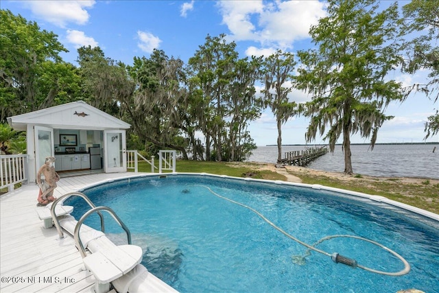 outdoor pool with an outbuilding, an exterior structure, and a water view