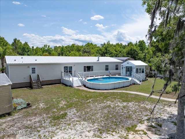 rear view of property with a deck, a lawn, and an outdoor pool