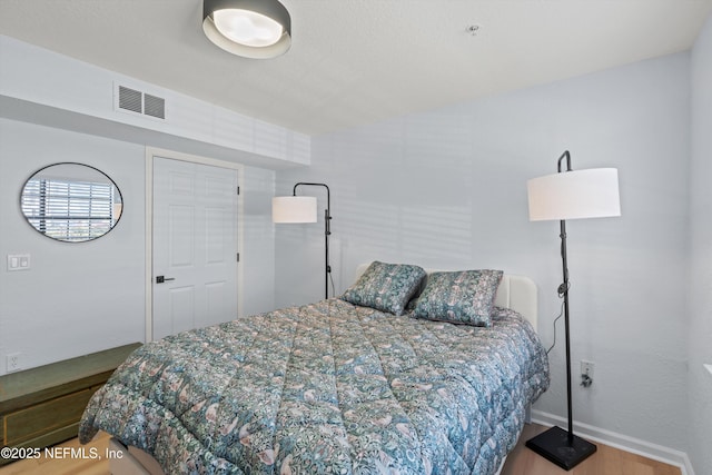 bedroom featuring visible vents, baseboards, and wood finished floors