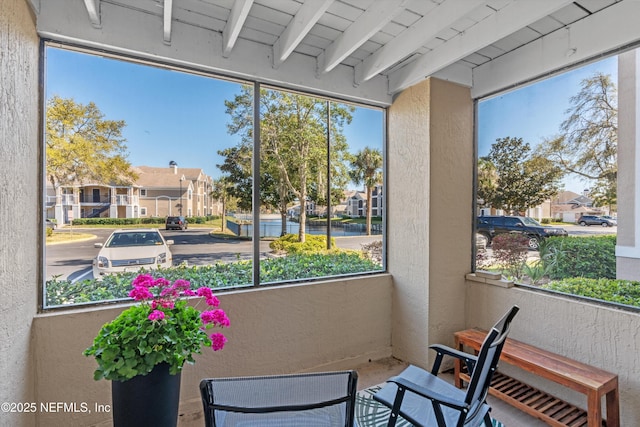 sunroom / solarium with beamed ceiling and a residential view