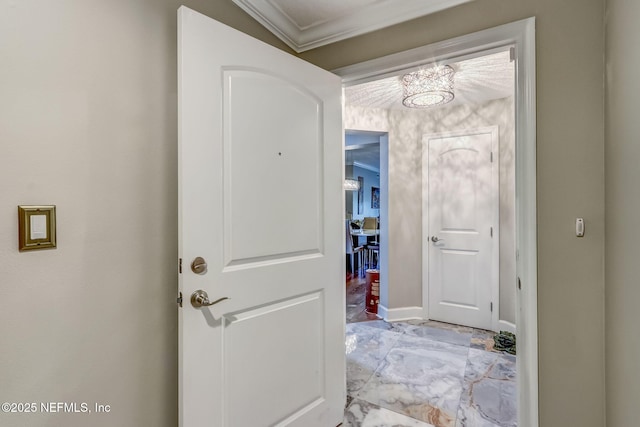 hall with baseboards, crown molding, and an inviting chandelier