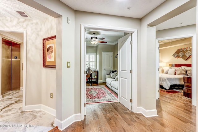 hall featuring baseboards, elevator, light wood-style floors, and visible vents