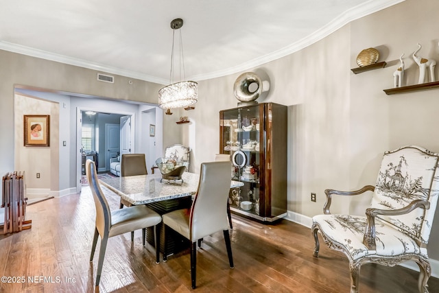 dining area featuring baseboards, crown molding, an inviting chandelier, and hardwood / wood-style flooring