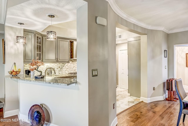 interior space featuring crown molding, baseboards, light wood finished floors, and a sink