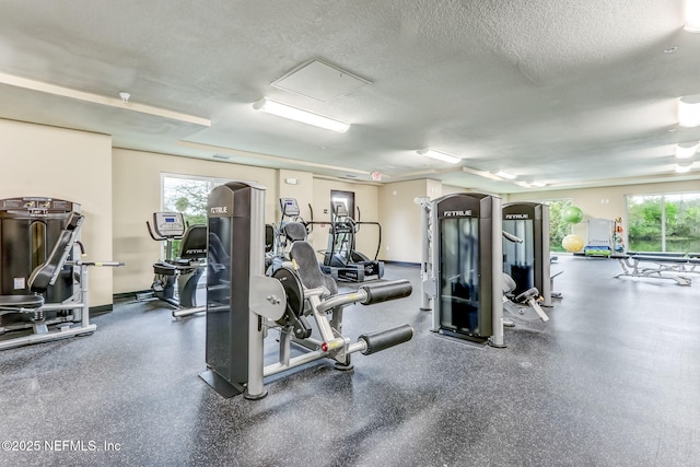 workout area featuring a textured ceiling and baseboards