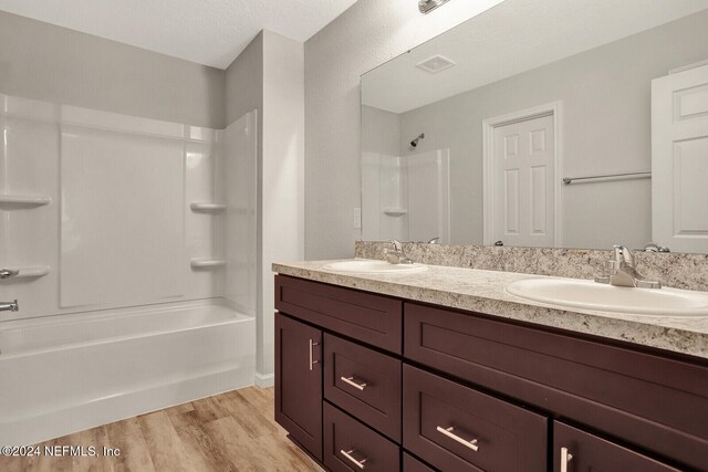 bathroom with a sink, shower / bath combination, wood finished floors, and double vanity